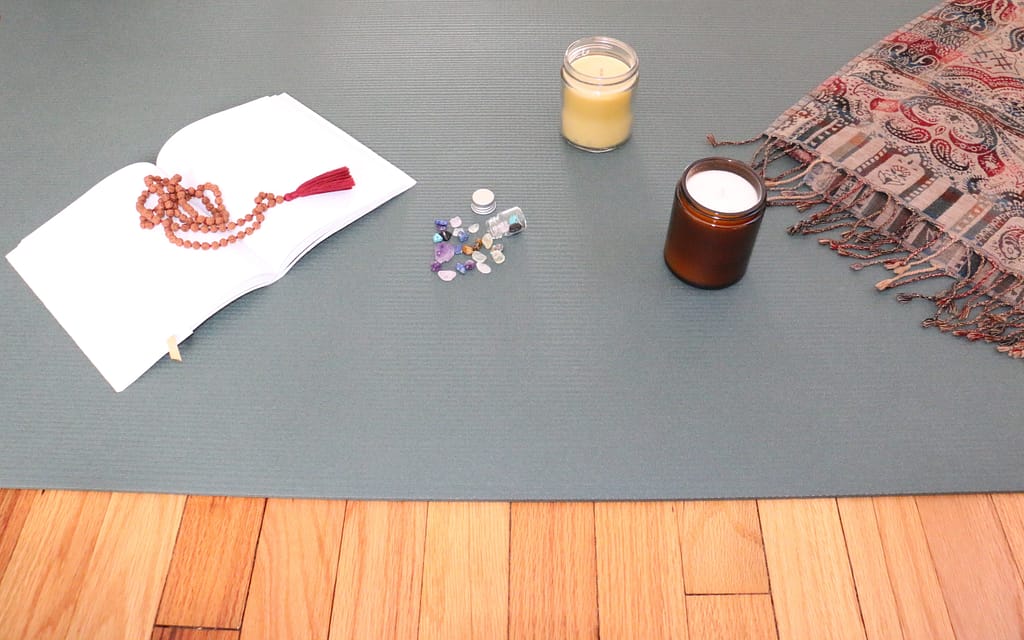 Open notebook and candles set atop of a yoga mat
